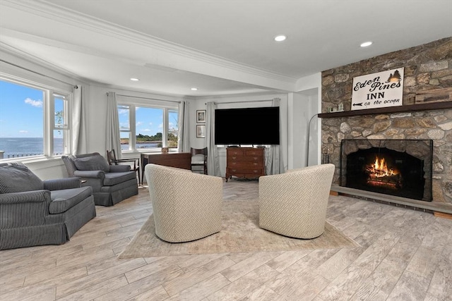 living room featuring recessed lighting, wood finished floors, crown molding, and a stone fireplace