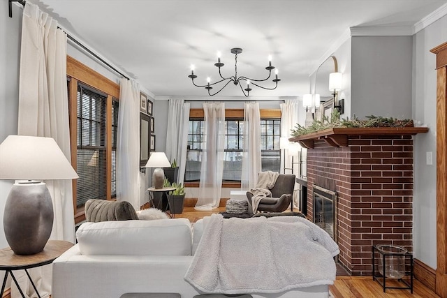 living room featuring a chandelier, light hardwood / wood-style flooring, a brick fireplace, and crown molding