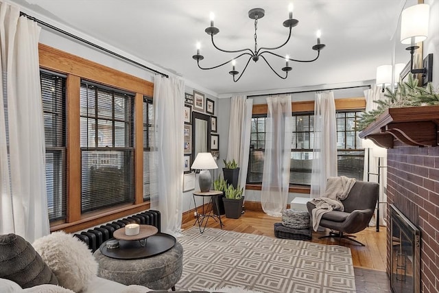 sitting room featuring an inviting chandelier, a brick fireplace, ornamental molding, brick wall, and hardwood / wood-style flooring