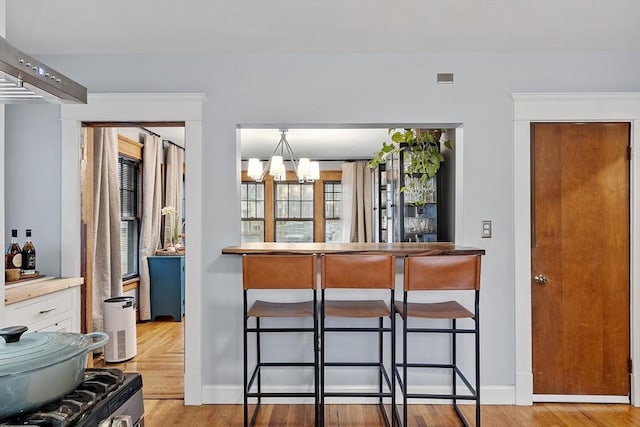 kitchen featuring a breakfast bar, light hardwood / wood-style floors, an inviting chandelier, and hanging light fixtures