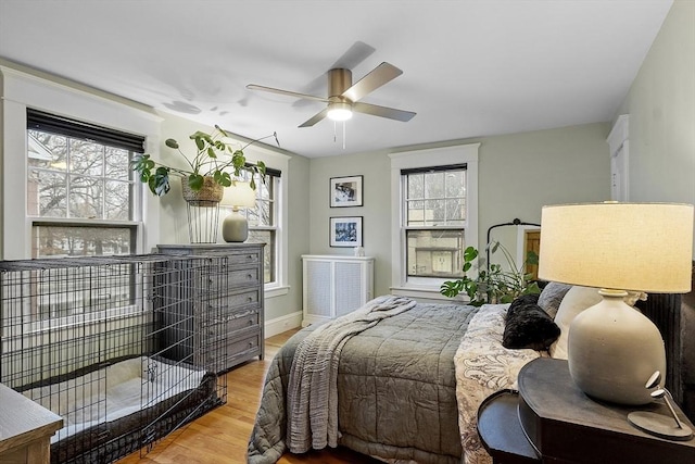 bedroom with ceiling fan, light hardwood / wood-style flooring, and multiple windows