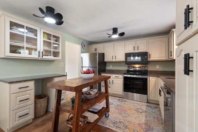 kitchen with ceiling fan, appliances with stainless steel finishes, dark hardwood / wood-style floors, and built in desk