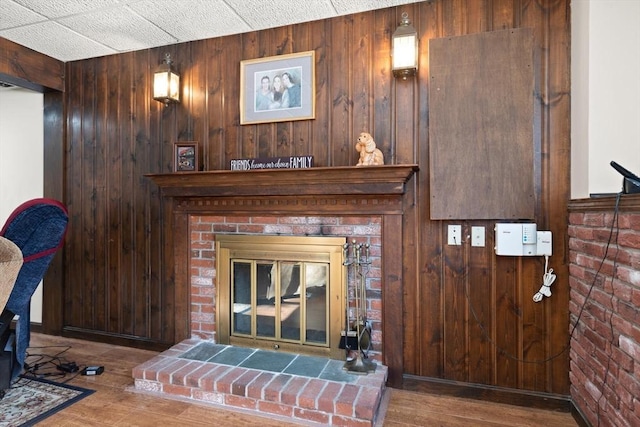 living room featuring hardwood / wood-style flooring, a brick fireplace, and wood walls