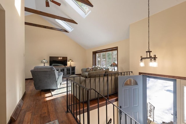 living room with dark wood-type flooring, vaulted ceiling with skylight, and an inviting chandelier