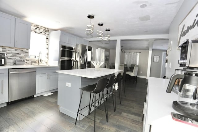 kitchen featuring a center island, a breakfast bar area, stainless steel appliances, light countertops, and a sink