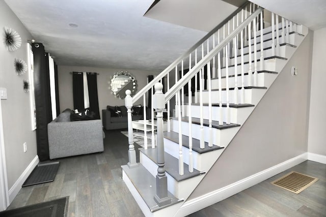 staircase with wood finished floors, visible vents, and baseboards