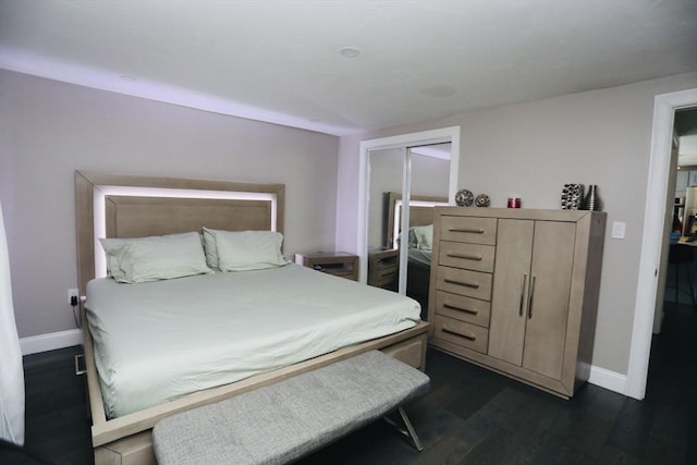 bedroom with dark wood-style flooring, a closet, and baseboards
