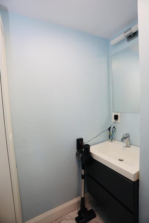 bathroom with marble finish floor, vanity, and baseboards