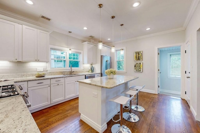 30 Pembroke St, Somerville, MA 02145 - kitchen featuring appliances with stainless steel finishes, a sink, a kitchen bar, white cabinetry, and ornamental molding
