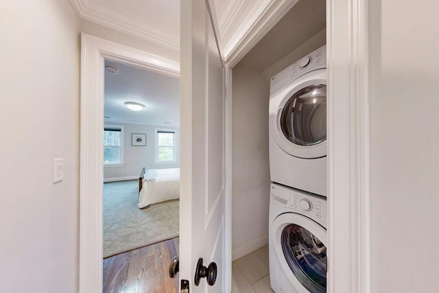 30 Pembroke St, Somerville, MA 02145 - laundry room with stacked washer and clothes dryer, crown molding, baseboards, and wood finished floors