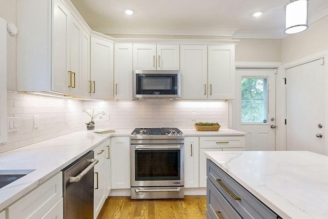 30 Pembroke St, Somerville, MA 02145 - kitchen featuring stainless steel appliances, light wood-type flooring, light stone counters, white cabinetry, and ornamental molding