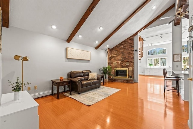 living area featuring ceiling fan, baseboard heating, wood finished floors, vaulted ceiling with beams, and a brick fireplace