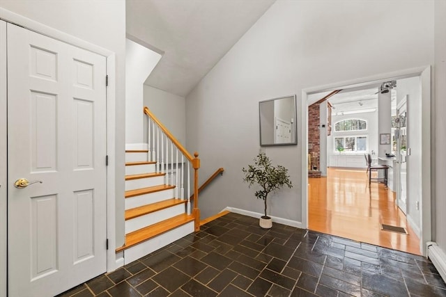 entrance foyer with visible vents, baseboards, a baseboard radiator, stone finish floor, and stairs