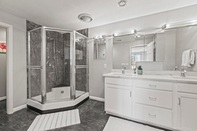full bath featuring a shower stall, double vanity, baseboards, and a sink