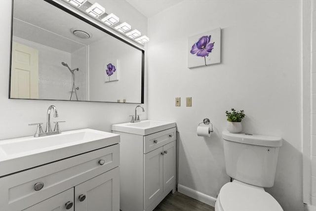 bathroom featuring walk in shower, a sink, toilet, and two vanities