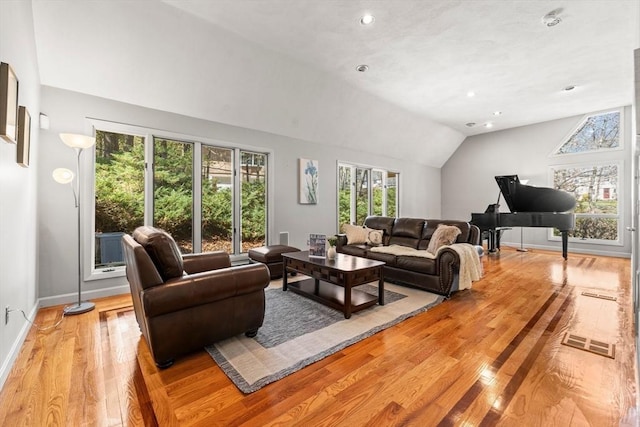 living room featuring visible vents, light wood-style flooring, baseboards, and lofted ceiling