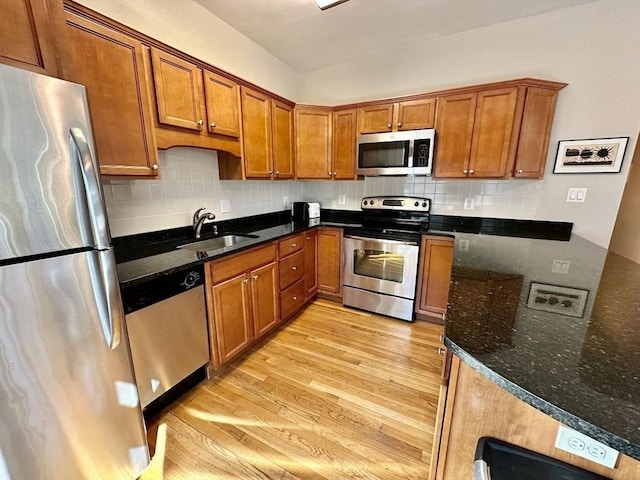 kitchen with a sink, stainless steel appliances, brown cabinets, and light wood finished floors