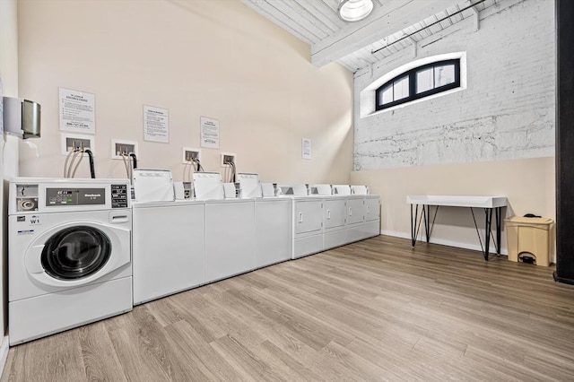 shared laundry area with independent washer and dryer, light wood-style floors, brick wall, and wood ceiling