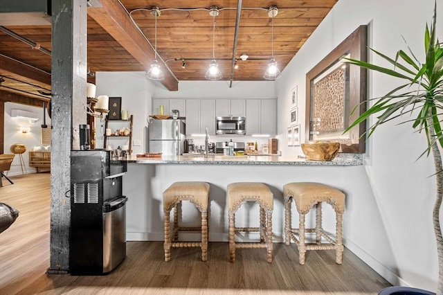 kitchen featuring a peninsula, wooden ceiling, wood finished floors, and stainless steel appliances