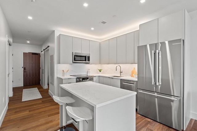 1515 Commonwealth Ave Unit 314, Boston, MA 02135 - kitchen with appliances with stainless steel finishes, wood finished floors, a kitchen island, backsplash, and recessed lighting