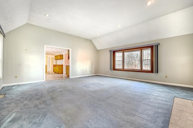 interior space featuring carpet flooring, baseboards, and lofted ceiling