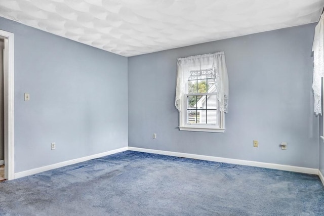 carpeted spare room featuring baseboards