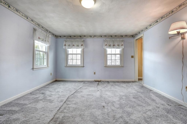 unfurnished room with carpet, baseboards, and a textured ceiling