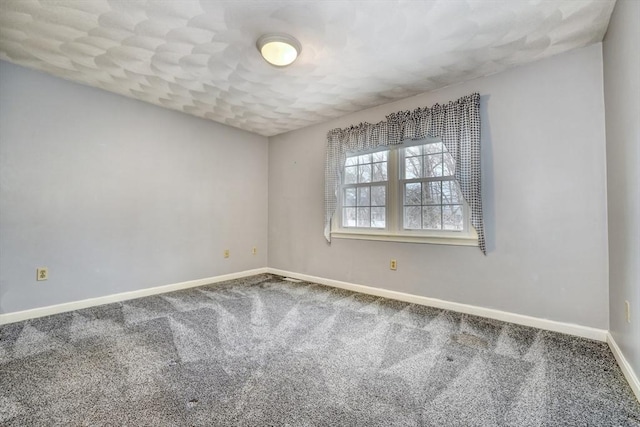 empty room featuring carpet and baseboards