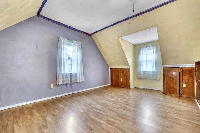 bonus room with baseboards, lofted ceiling, and wood finished floors