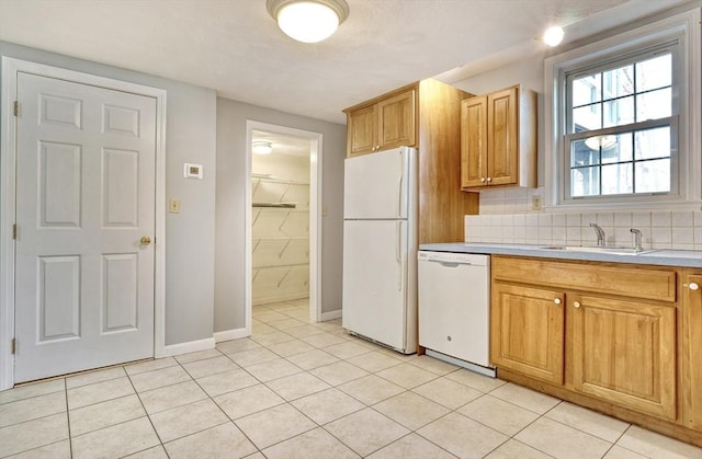 kitchen with tasteful backsplash, light countertops, light tile patterned flooring, white appliances, and a sink