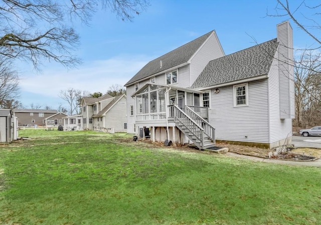 rear view of house with stairway, roof with shingles, a chimney, a yard, and a sunroom