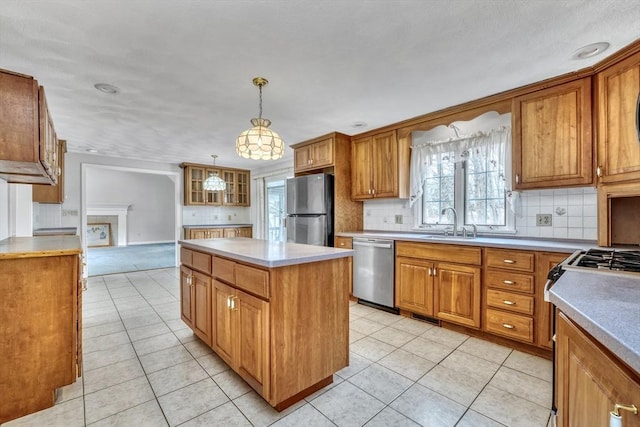 kitchen with brown cabinets, appliances with stainless steel finishes, a center island, and a sink