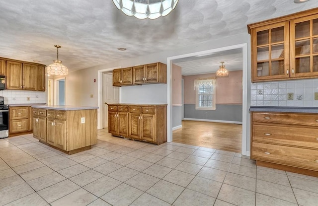 kitchen with light tile patterned flooring, decorative backsplash, stainless steel range with electric cooktop, and brown cabinetry