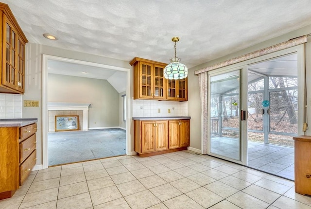 kitchen featuring tasteful backsplash, glass insert cabinets, brown cabinets, and light tile patterned floors