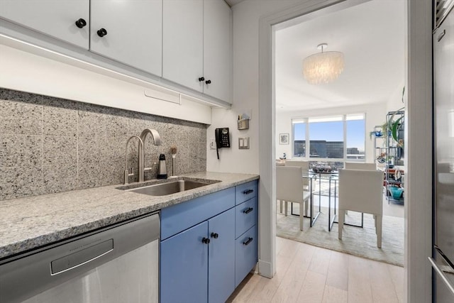 kitchen with blue cabinets, white cabinetry, sink, and stainless steel dishwasher