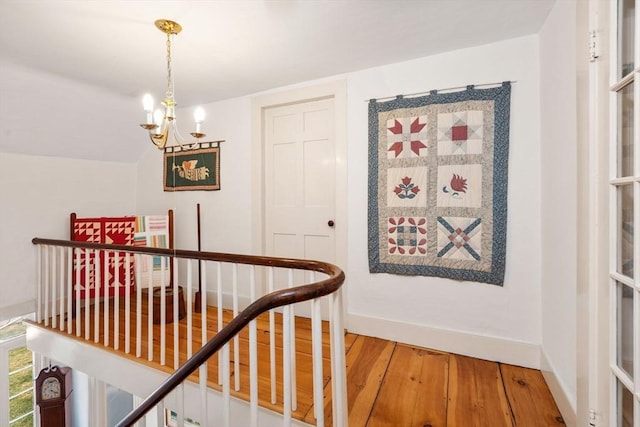 hallway featuring a chandelier, wood-type flooring, and lofted ceiling