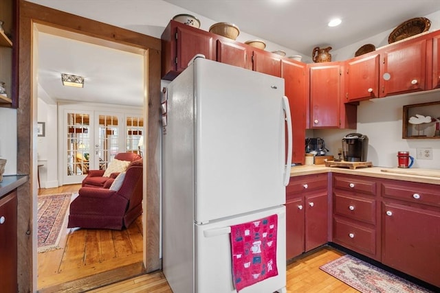 kitchen with light wood-type flooring, french doors, and white refrigerator