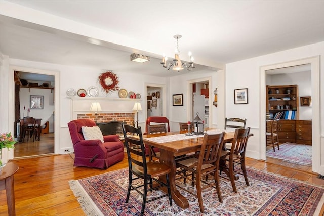 dining area with a fireplace, a chandelier, and light hardwood / wood-style floors