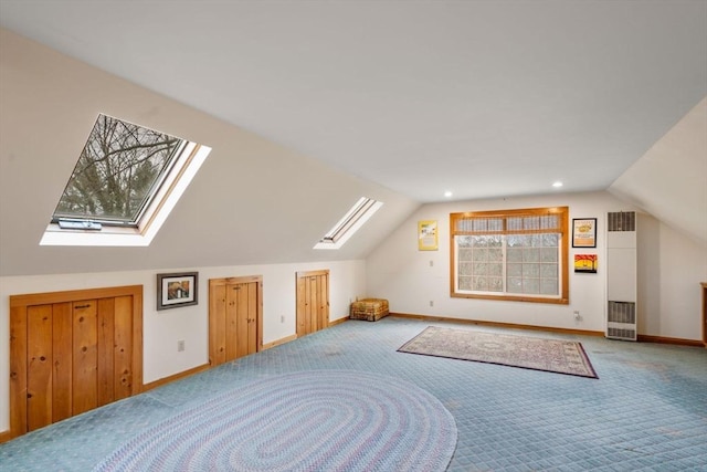 additional living space featuring carpet flooring, vaulted ceiling with skylight, and a healthy amount of sunlight