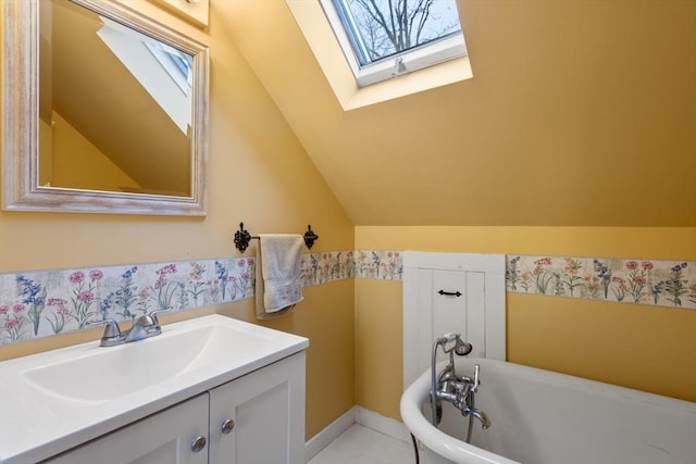 bathroom featuring vanity, a tub to relax in, and vaulted ceiling with skylight