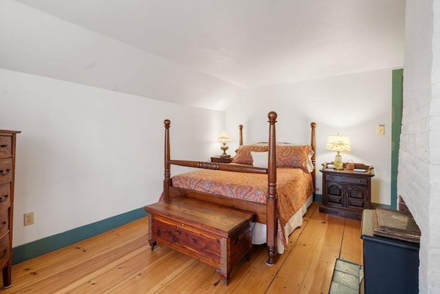 bedroom with light hardwood / wood-style floors and lofted ceiling