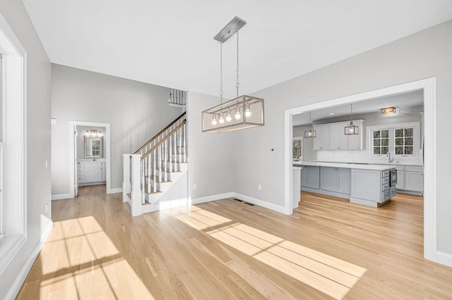 interior space featuring light wood-type flooring, stairs, and baseboards