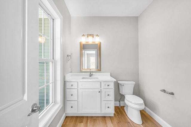 bathroom with vanity, wood finished floors, toilet, and baseboards