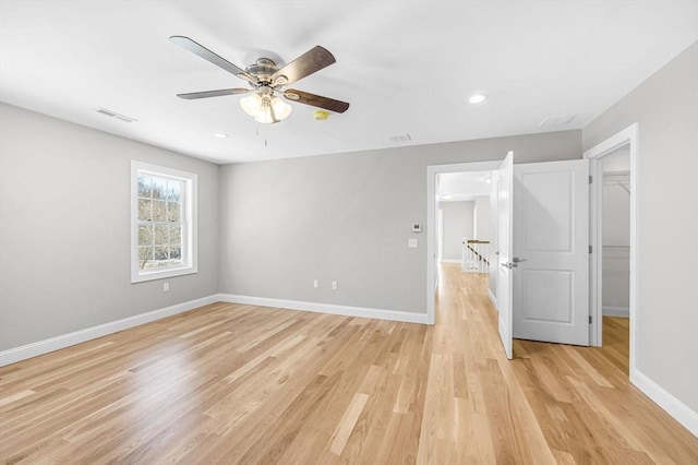 unfurnished bedroom with a walk in closet, baseboards, visible vents, and light wood finished floors