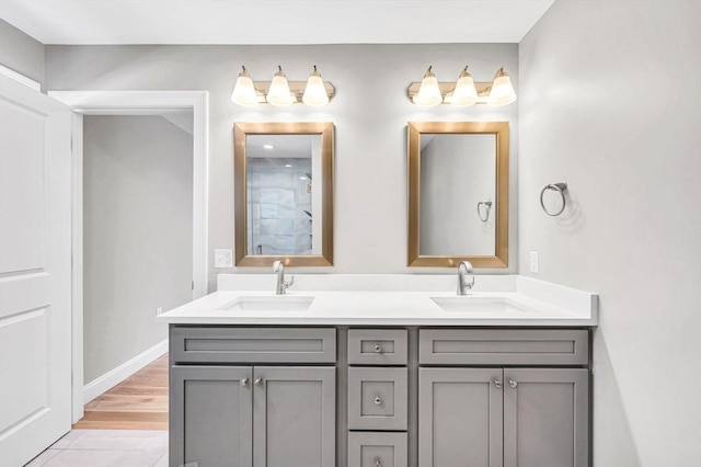 bathroom featuring wood finished floors, a sink, baseboards, and double vanity