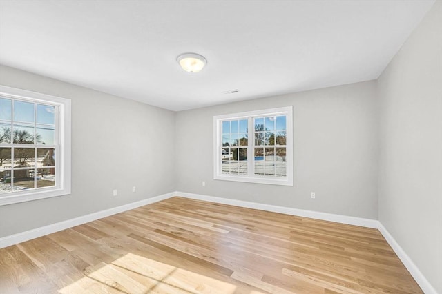 empty room featuring a healthy amount of sunlight, light wood-style floors, and baseboards