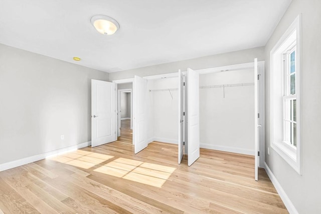 unfurnished bedroom featuring multiple closets, light wood-type flooring, and baseboards