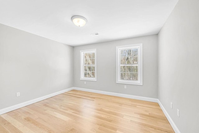 spare room with visible vents, light wood-style flooring, and baseboards