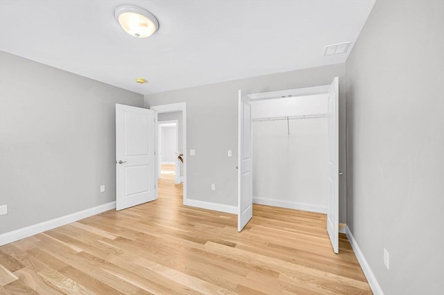 unfurnished bedroom with baseboards, a closet, visible vents, and light wood-style floors