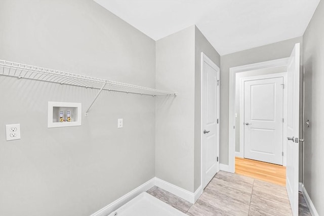 laundry area with laundry area, hookup for a washing machine, electric dryer hookup, and baseboards